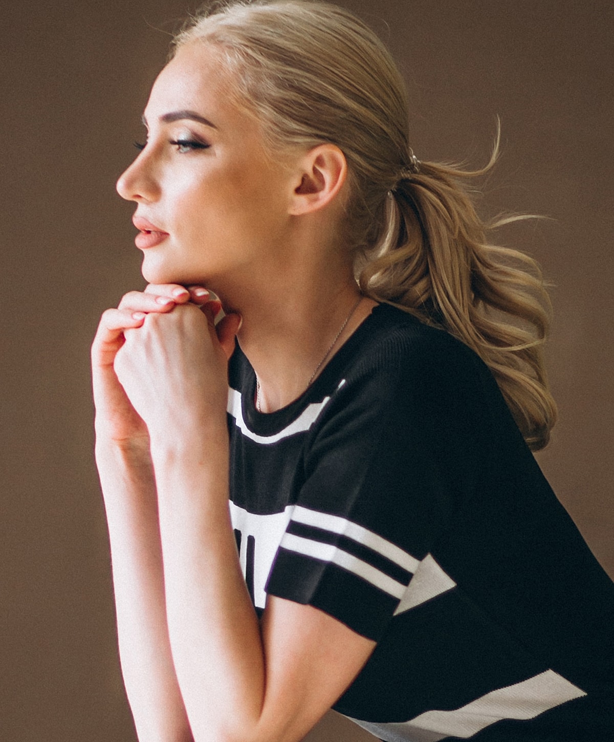 Woman in profile with hands clasped thoughtfully.