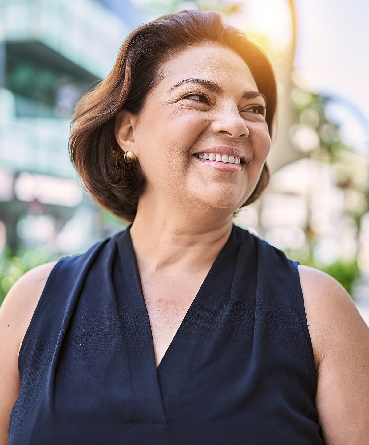 Smiling woman outdoors with sunlight background.