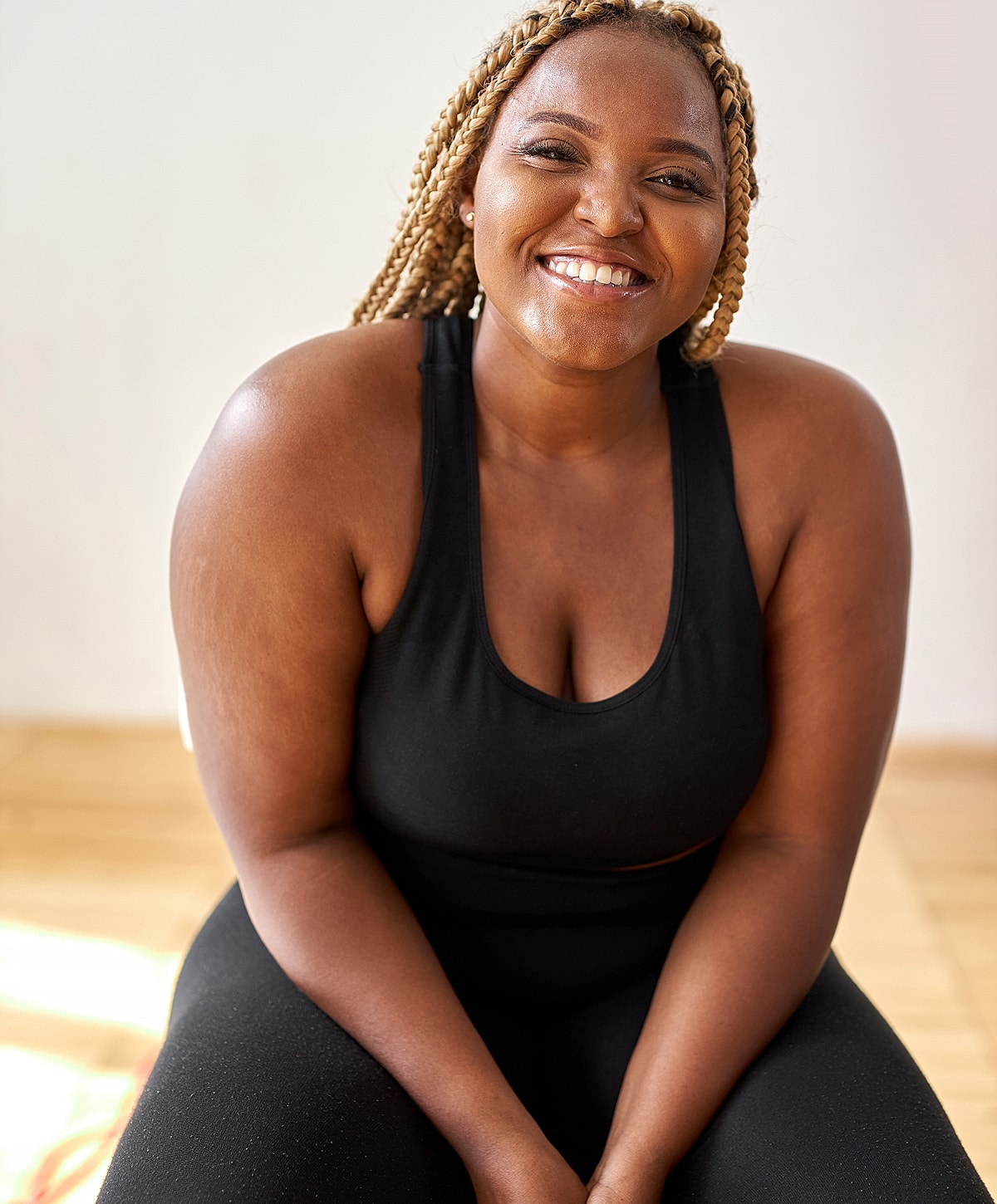 Smiling woman in workout attire, seated indoors.