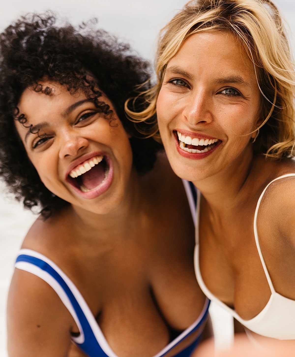 Two friends joyfully posing together at the beach.