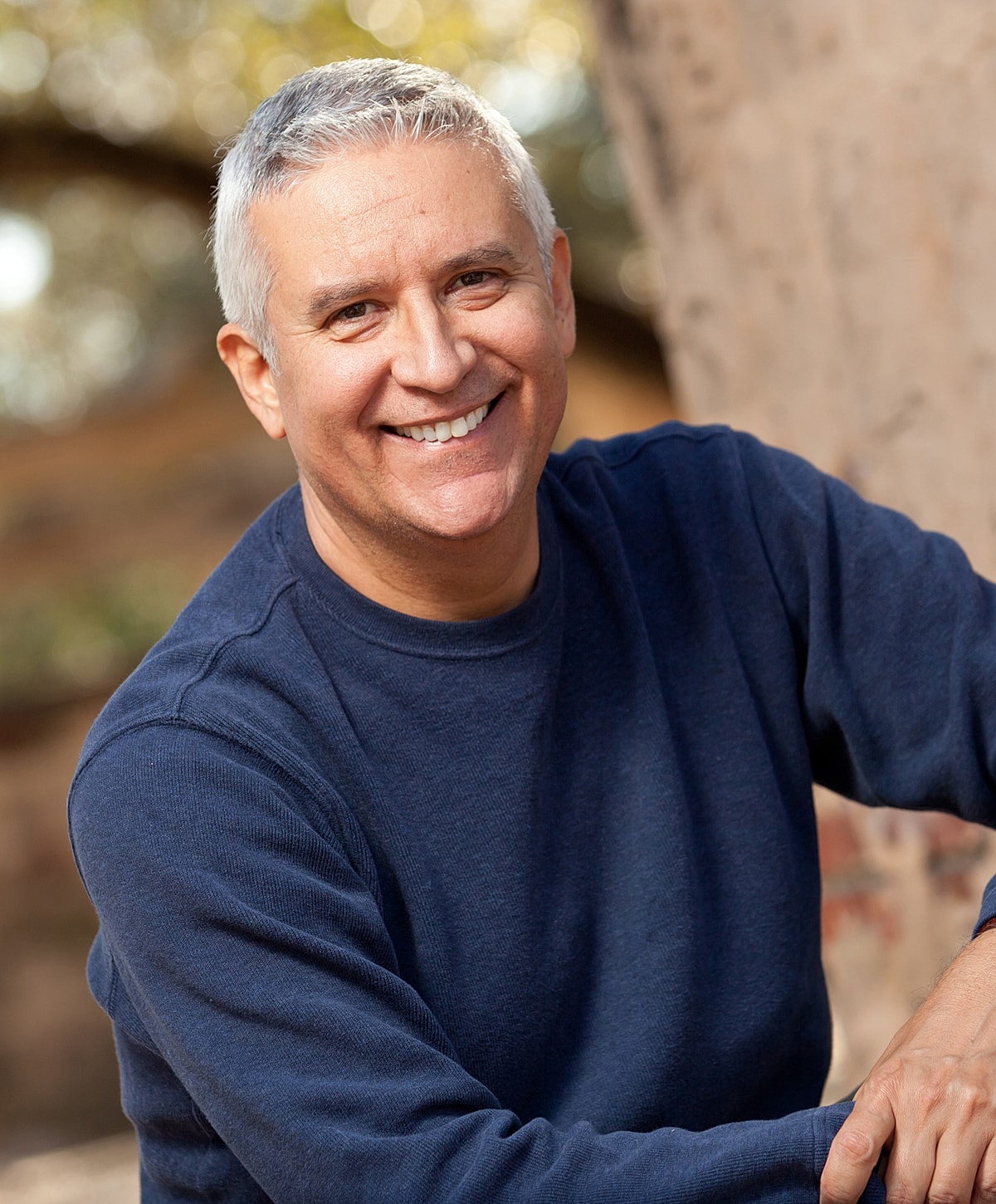 Smiling man in a blue sweater outdoors.