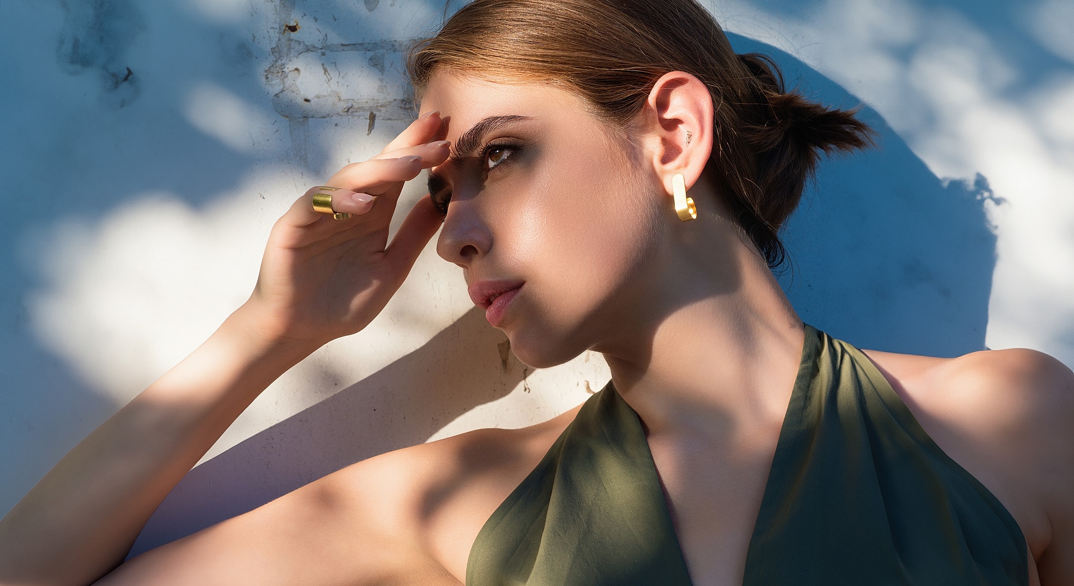 Woman posing in sunlight with elegant jewelry.