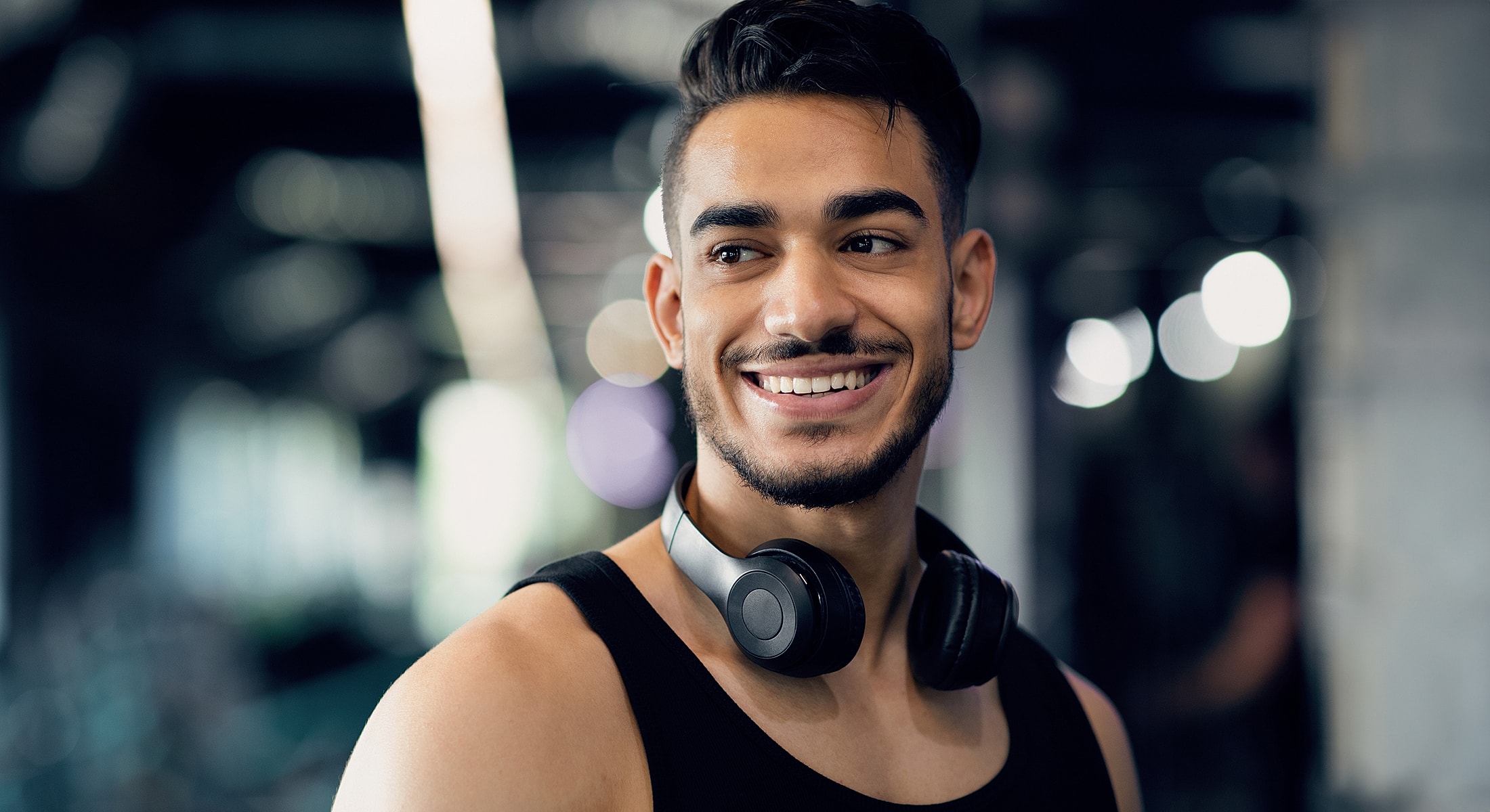 Smiling man with headphones in gym setting.