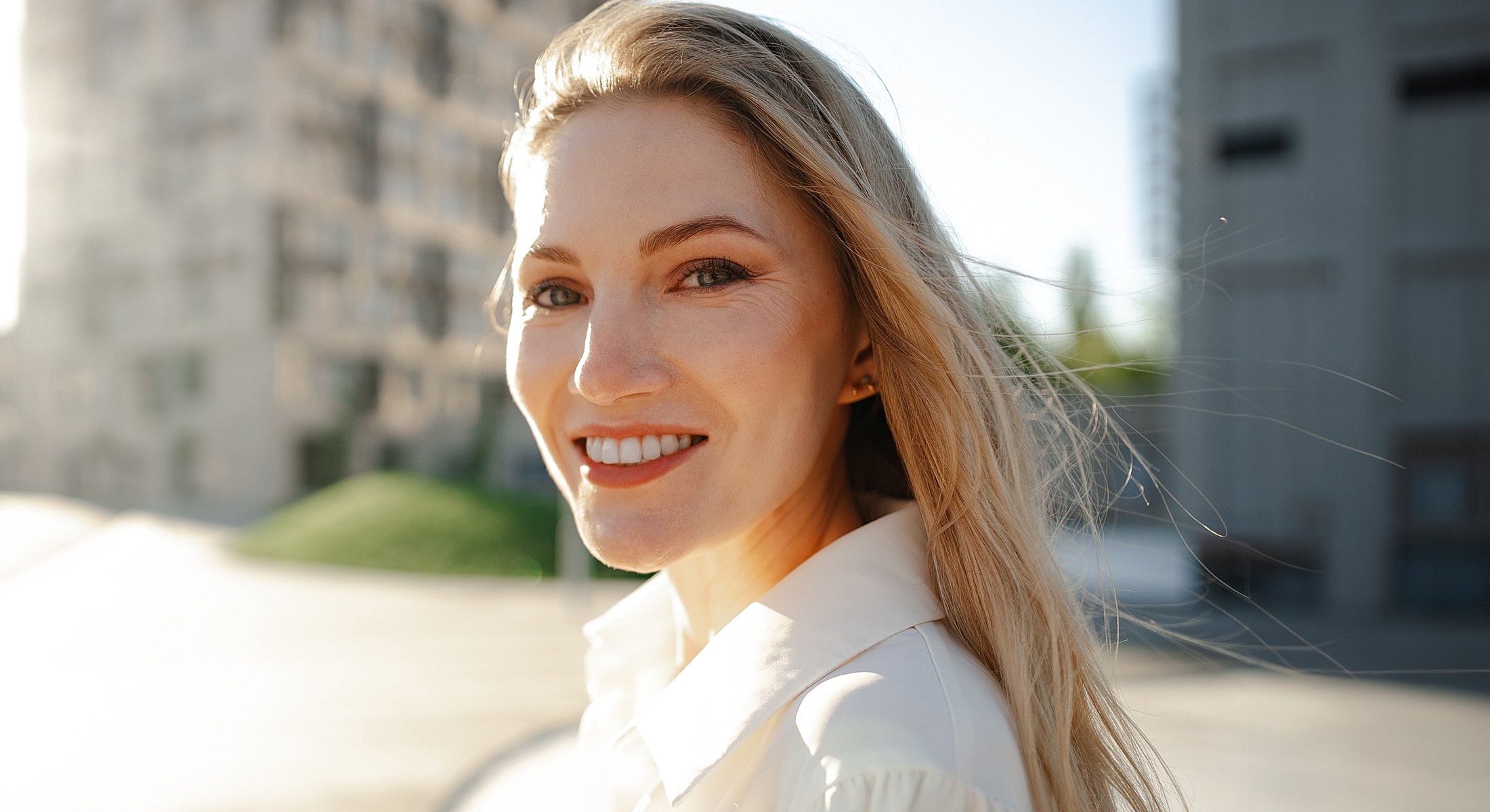 Smiling woman in sunny urban setting.